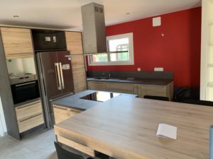 Réalisations Cusines DEBARD - Cuisine avec ilot et hotte plafond moderne et mur rouge